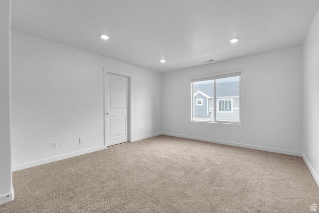 spare room with carpet flooring, recessed lighting, baseboards, and visible vents