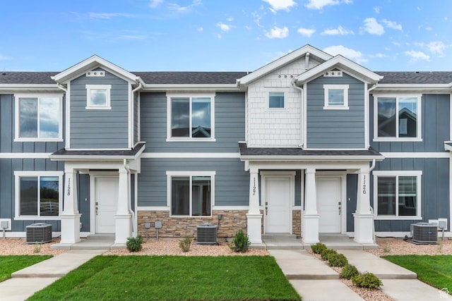 view of front of home with a front lawn, stone siding, and cooling unit