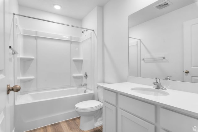 bathroom with vanity, toilet, shower / washtub combination, wood finished floors, and visible vents