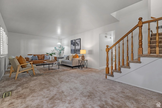 living room featuring baseboards, visible vents, carpet, and stairway