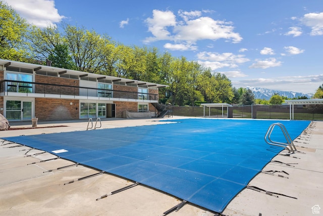 view of swimming pool with fence, a fenced in pool, a mountain view, and a patio area