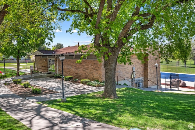 view of home's exterior featuring brick siding, fence, and a yard