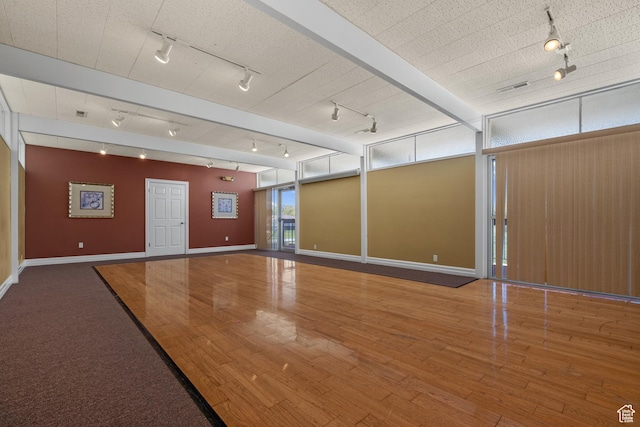 unfurnished room with track lighting, baseboards, wood finished floors, and visible vents