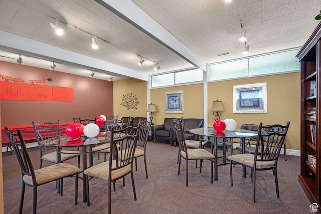 carpeted dining area featuring rail lighting, visible vents, and baseboards
