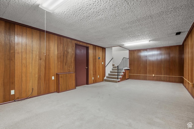 finished basement featuring carpet, stairs, and wood walls