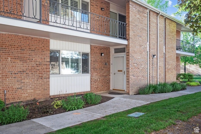 property entrance featuring brick siding and a balcony