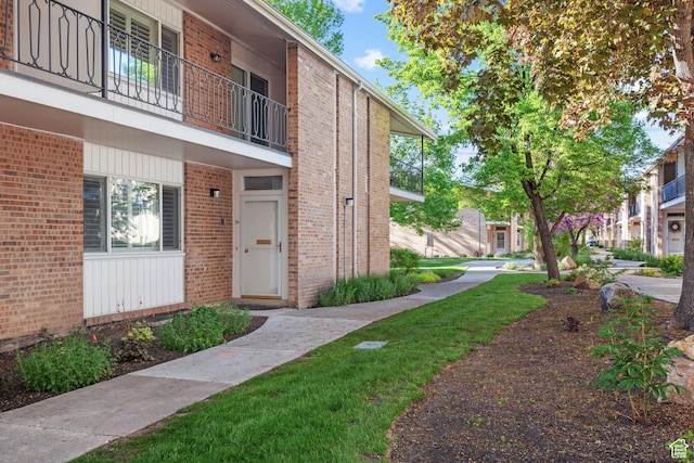 doorway to property with a balcony and brick siding