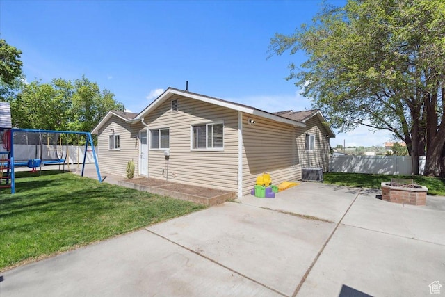 bungalow-style home with central AC, fence, a front yard, a patio, and a trampoline