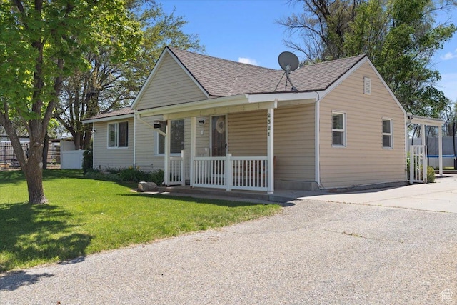 view of front facade featuring a porch, a front yard, driveway, and roof with shingles