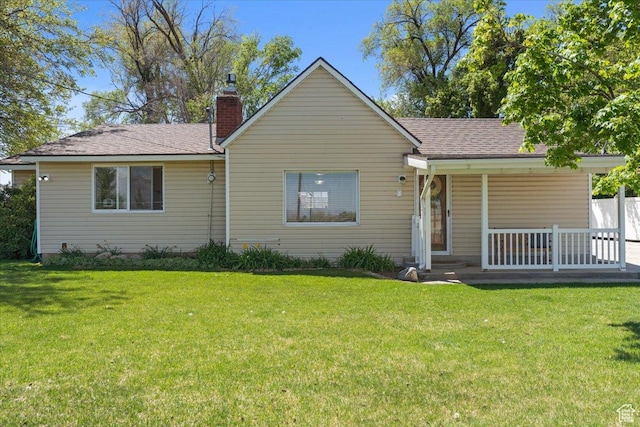 rear view of house with a lawn, a shingled roof, a chimney, and a porch