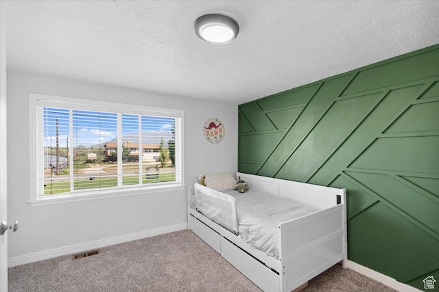 bedroom with baseboards, carpet flooring, a textured ceiling, and visible vents