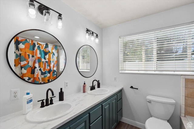 bathroom featuring double vanity, a sink, a shower with shower curtain, and toilet