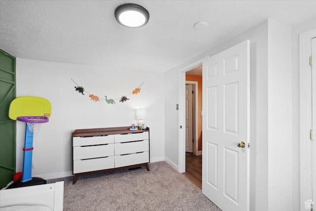 carpeted bedroom featuring baseboards and a textured ceiling