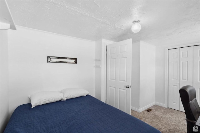 carpeted bedroom with visible vents, a textured ceiling, baseboards, and a closet