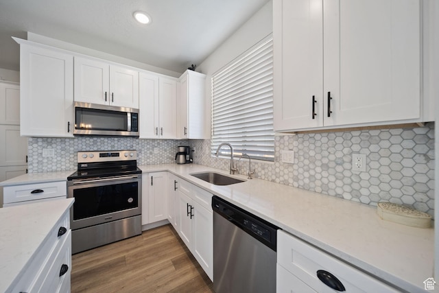 743 N 690 E, Tooele, UT 84074 - kitchen featuring white cabinets, appliances with stainless steel finishes, light stone counters, a sink, and backsplash