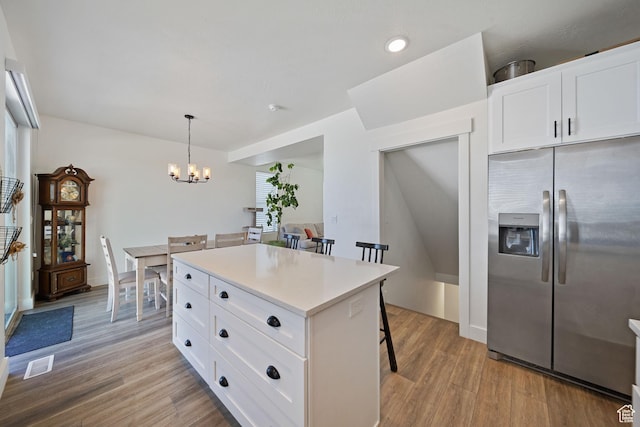 743 N 690 E, Tooele, UT 84074 - kitchen with an inviting chandelier, a kitchen breakfast bar, light wood-style flooring, stainless steel refrigerator with ice dispenser, and visible vents