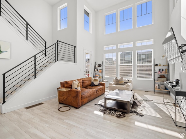 living area with baseboards, a high ceiling, wood finished floors, and stairway