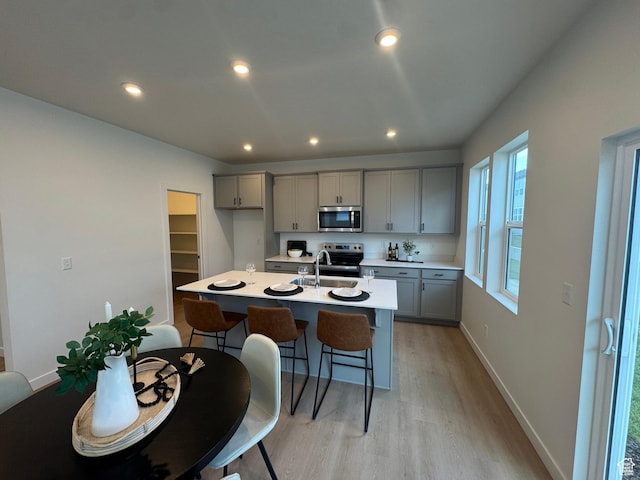 3620 N Stallion St Unit 349, Eagle Mountain, UT 84005 - kitchen featuring stainless steel appliances, gray cabinetry, light wood-style flooring, light countertops, and a breakfast bar
