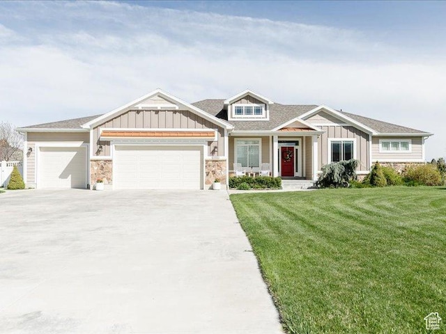craftsman-style home with board and batten siding, stone siding, an attached garage, and a front yard
