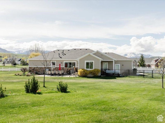 back of property featuring a yard, a patio, fence, and a mountain view