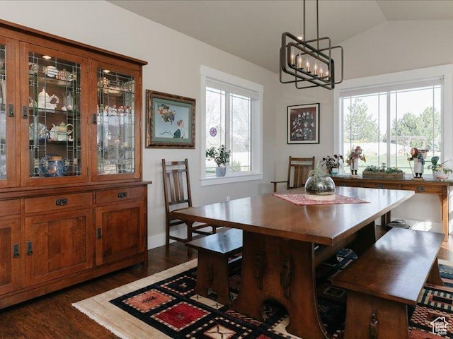 dining room with an inviting chandelier, vaulted ceiling, and dark wood-style floors