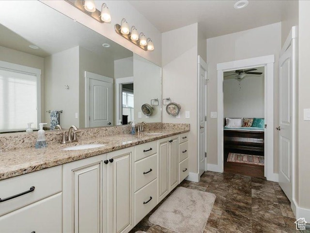 bathroom with double vanity, a sink, baseboards, and ensuite bath