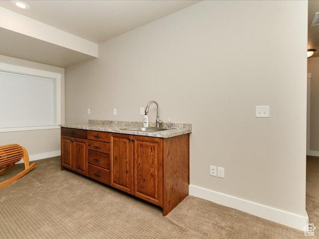 bar with baseboards, light colored carpet, and a sink