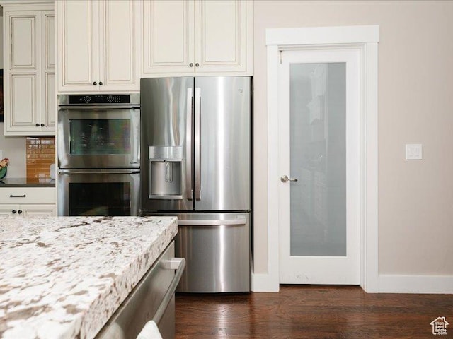 kitchen featuring decorative backsplash, light stone countertops, baseboards, dark wood-type flooring, and stainless steel appliances