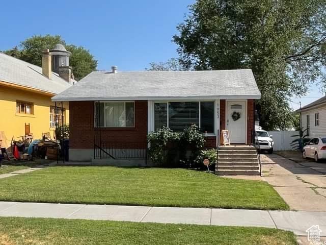 view of front facade with concrete driveway, brick siding, and a front lawn