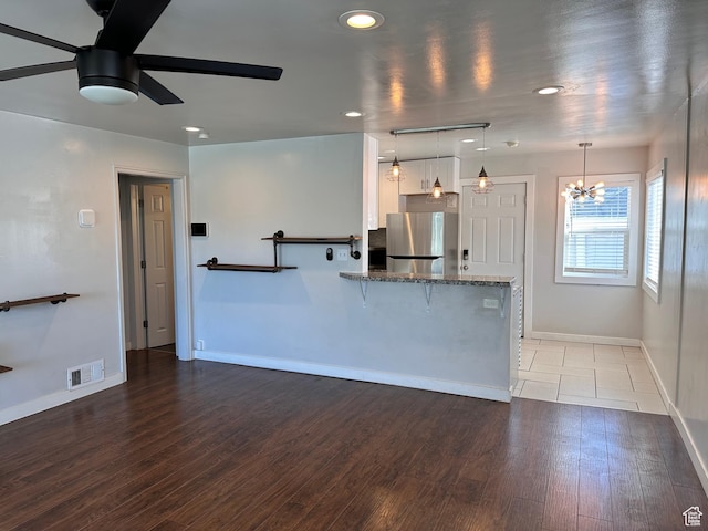 953 E 24th St, Ogden, UT 84401 - kitchen with ceiling fan with notable chandelier, dark stone countertops, freestanding refrigerator, visible vents, and baseboards
