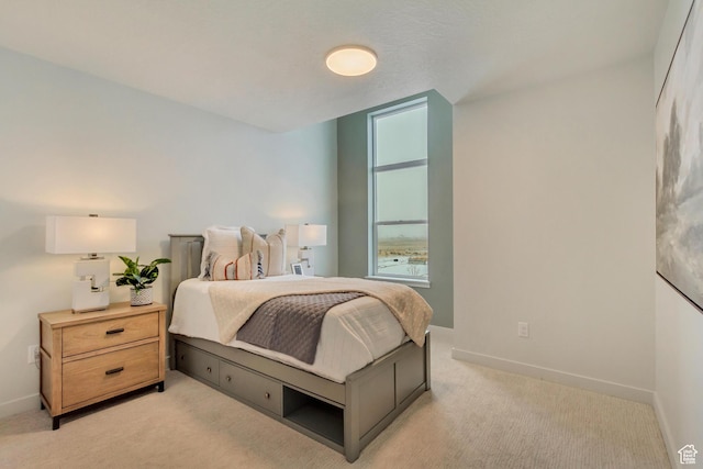 bedroom with baseboards and light carpet