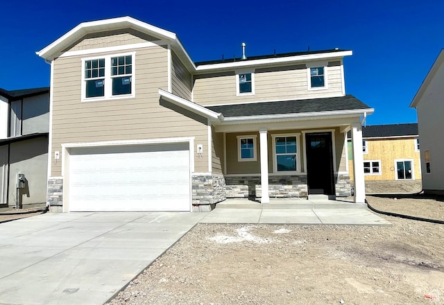 view of front of house featuring a porch, a garage, stone siding, and driveway