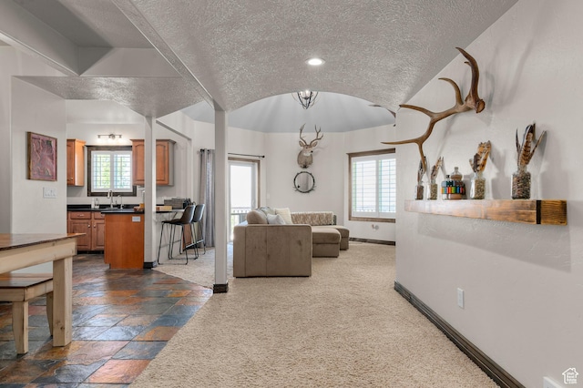 294 W Farmside Dr S, Saratoga Springs, UT 84045 - living room with a textured ceiling, healthy amount of natural light, baseboards, stone tile flooring, and vaulted ceiling