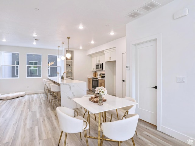dining area featuring baseboards, visible vents, and light wood-style floors