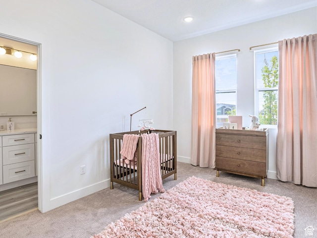 bedroom with baseboards, light carpet, recessed lighting, and a crib