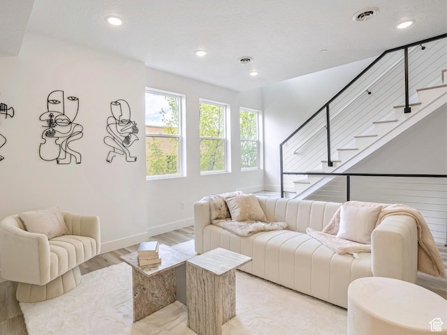 living area with light wood-style floors, recessed lighting, baseboards, visible vents, and stairway