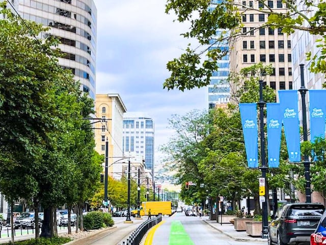 view of road with traffic lights, curbs, street lights, and sidewalks