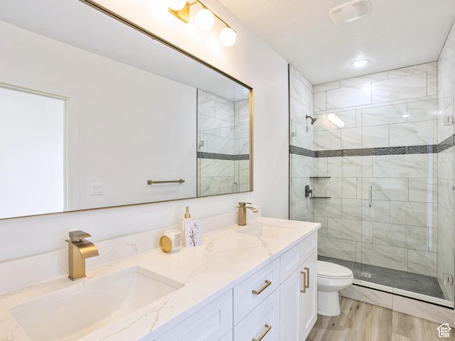 bathroom featuring wood finished floors, a sink, a stall shower, and toilet