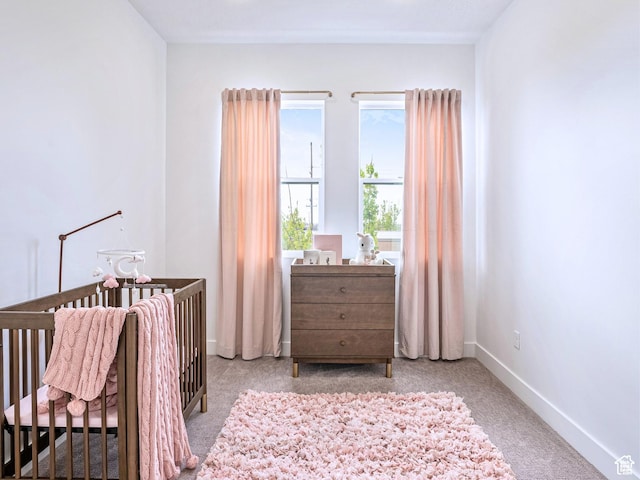 carpeted bedroom with a nursery area and baseboards