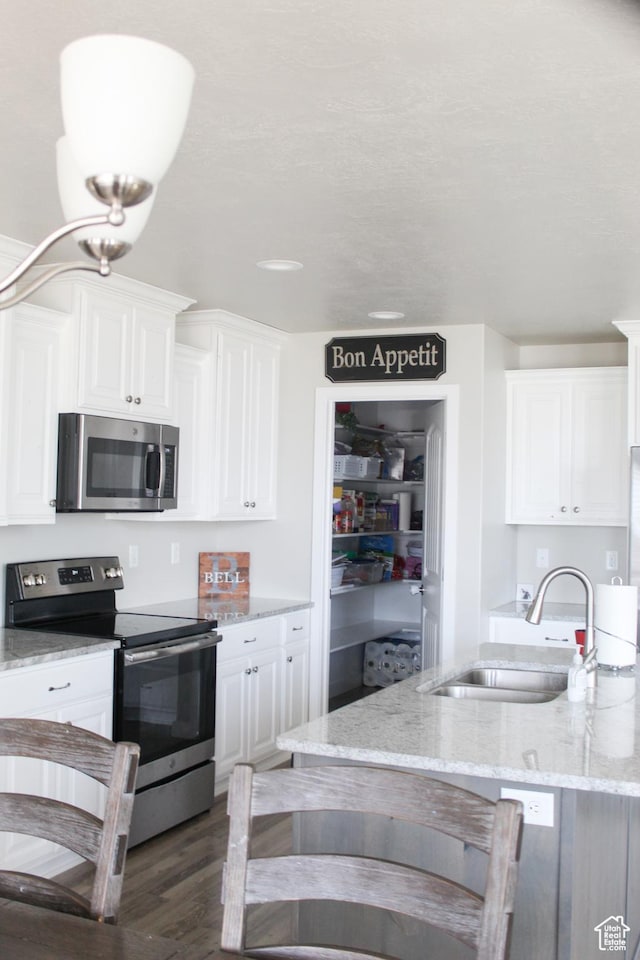 2447 N 2950 W, Plain City, UT 84404 - kitchen with appliances with stainless steel finishes, a sink, white cabinets, and light stone countertops