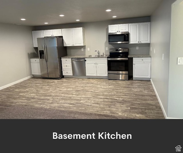 2447 N 2950 W, Plain City, UT 84404 - kitchen with stainless steel appliances, a sink, wood finished floors, white cabinetry, and baseboards