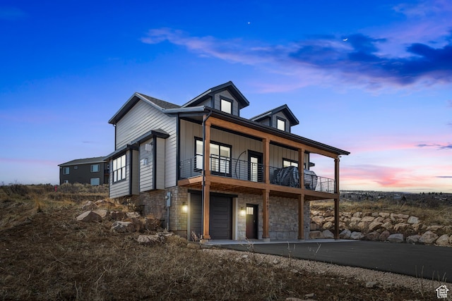 3467 S Porcupine Cir, Garden City, UT 84028 - rear view of house with an attached garage, board and batten siding, a balcony, and stone siding