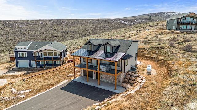 3467 S Porcupine Cir, Garden City, UT 84028 - exterior space featuring an attached garage, driveway, a balcony, and stone siding