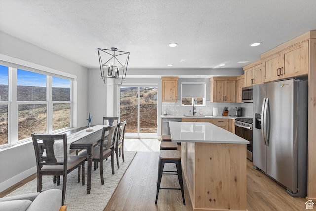 3467 S Porcupine Cir, Garden City, UT 84028 - kitchen with an inviting chandelier, light brown cabinets, light wood-style floors, a sink, and appliances with stainless steel finishes
