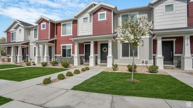 multi unit property featuring a porch, a front lawn, and stone siding