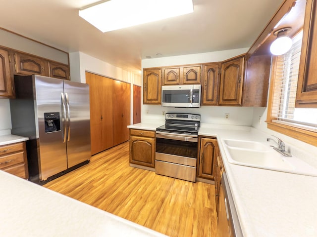 kitchen featuring light countertops, appliances with stainless steel finishes, a sink, and light wood-type flooring