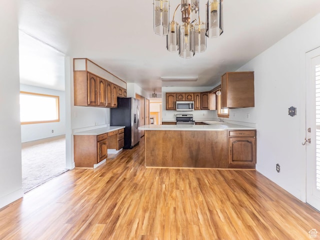 kitchen with brown cabinetry, stainless steel appliances, and light wood-type flooring