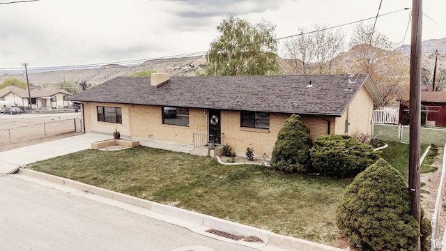 single story home featuring fence, a front yard, roof with shingles, a chimney, and brick siding