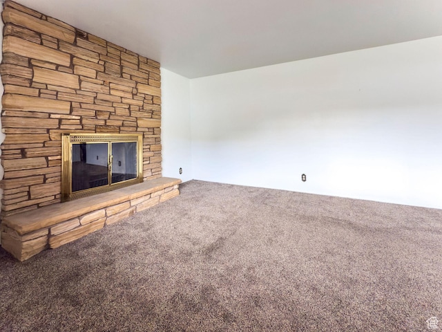 unfurnished living room featuring a stone fireplace and carpet flooring