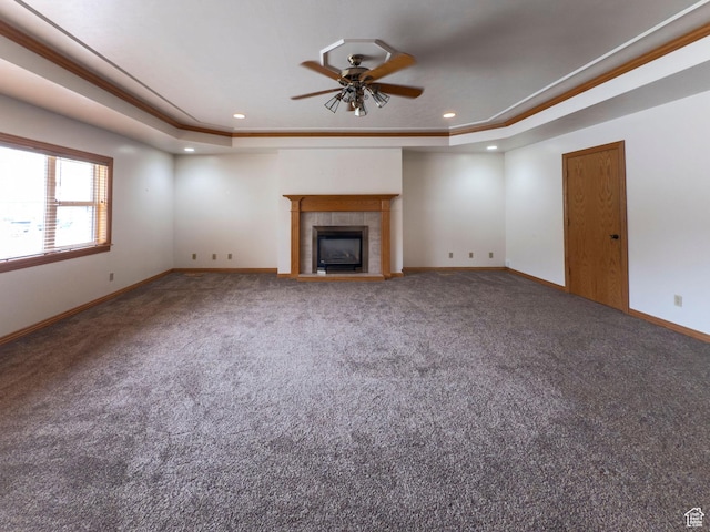 unfurnished living room featuring a ceiling fan, a tray ceiling, and carpet flooring